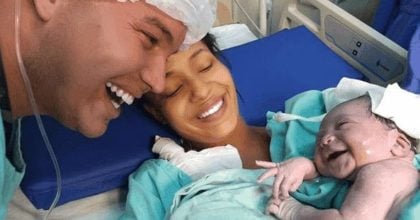 A newborn baby girl smiles as she recognizes the voice of her father.