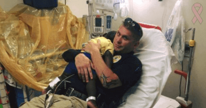 Police officer comforting lost toddler while the hospital staff is doing a check up.