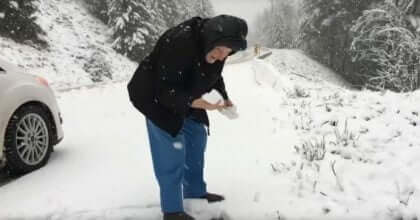 101 year old woman gets out the car to play in the snow.