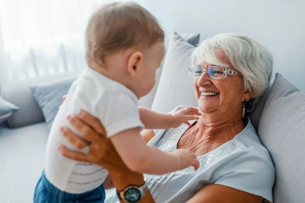 A grandmother smiling while holding a baby | Source: Shutterstock