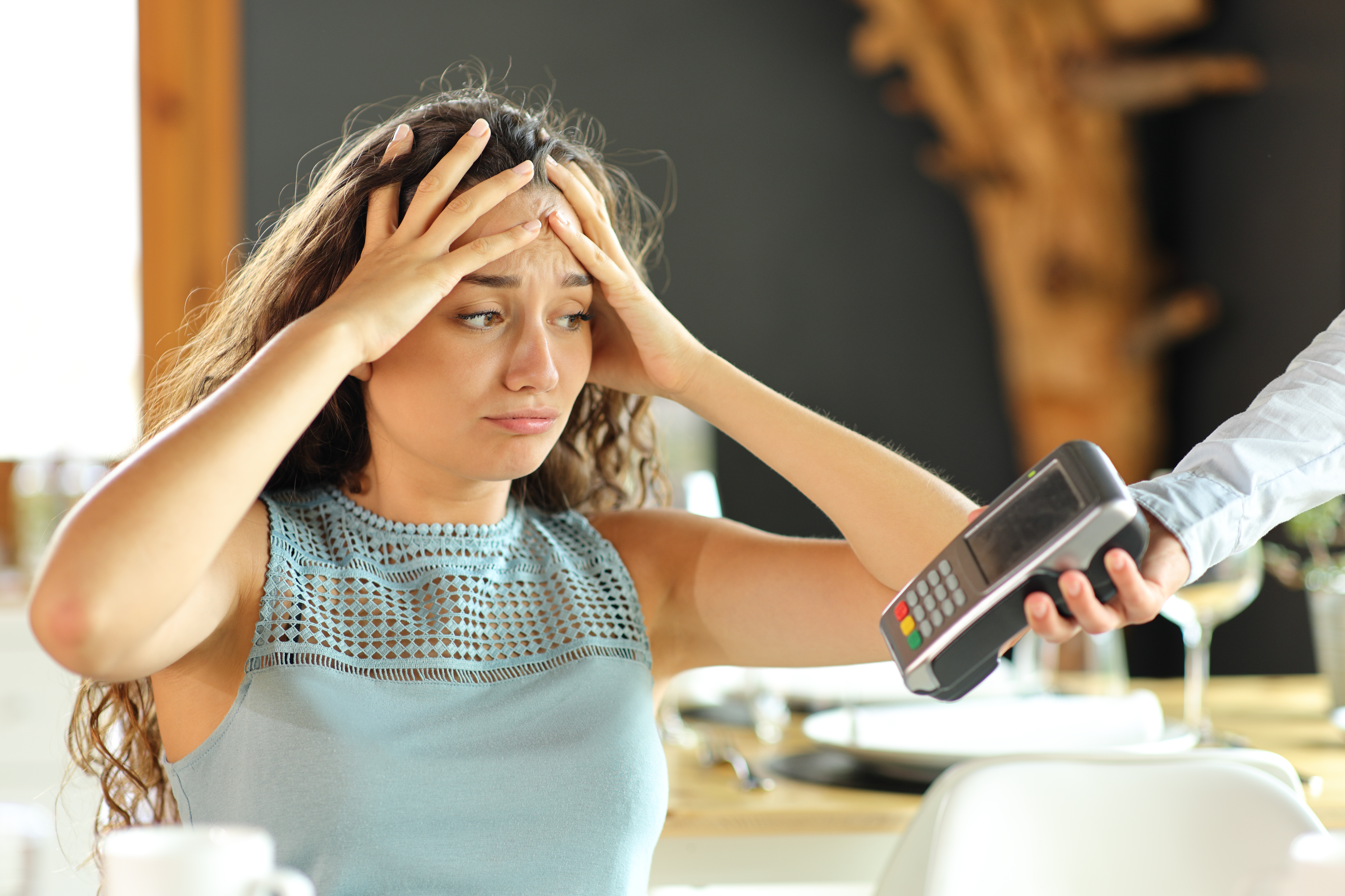 A woman looking desperate as a credit card machine is handed to her | Source: Shutterstock