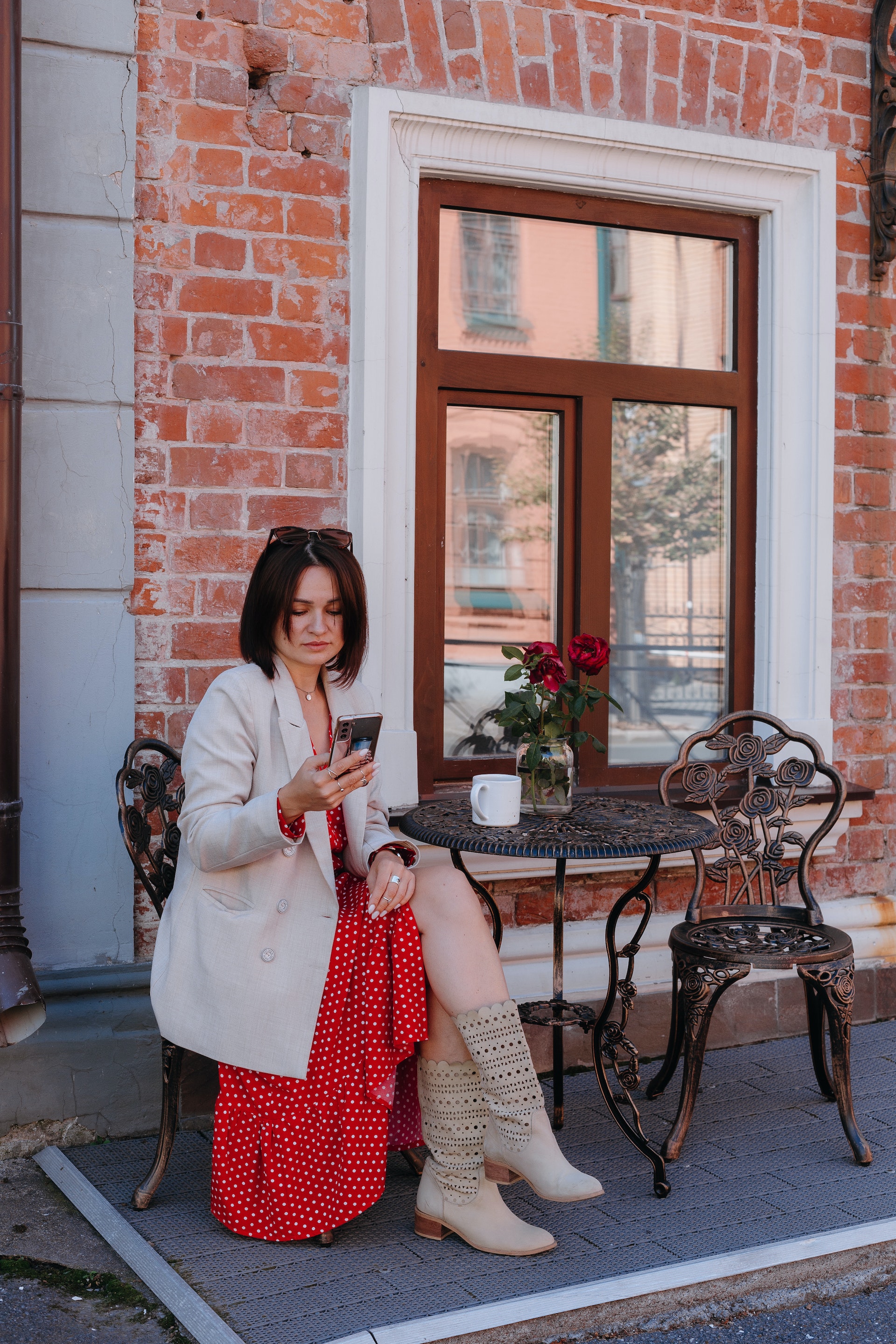 A woman sitting at a sidewalk cafe while checking her mobile phone | Source: Pexels