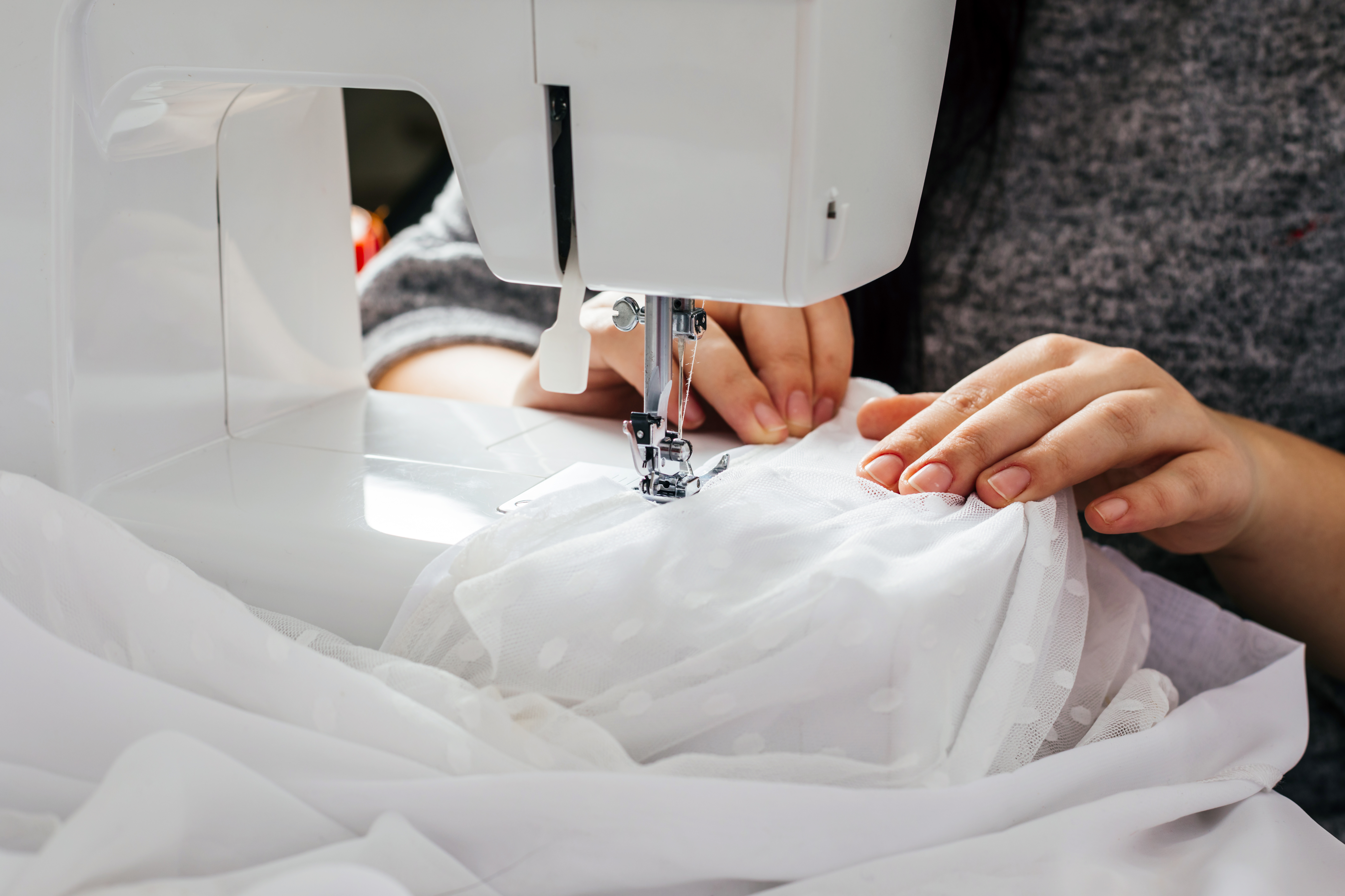 A seamstress sewing a wedding dress. | Source: Shutterstock
