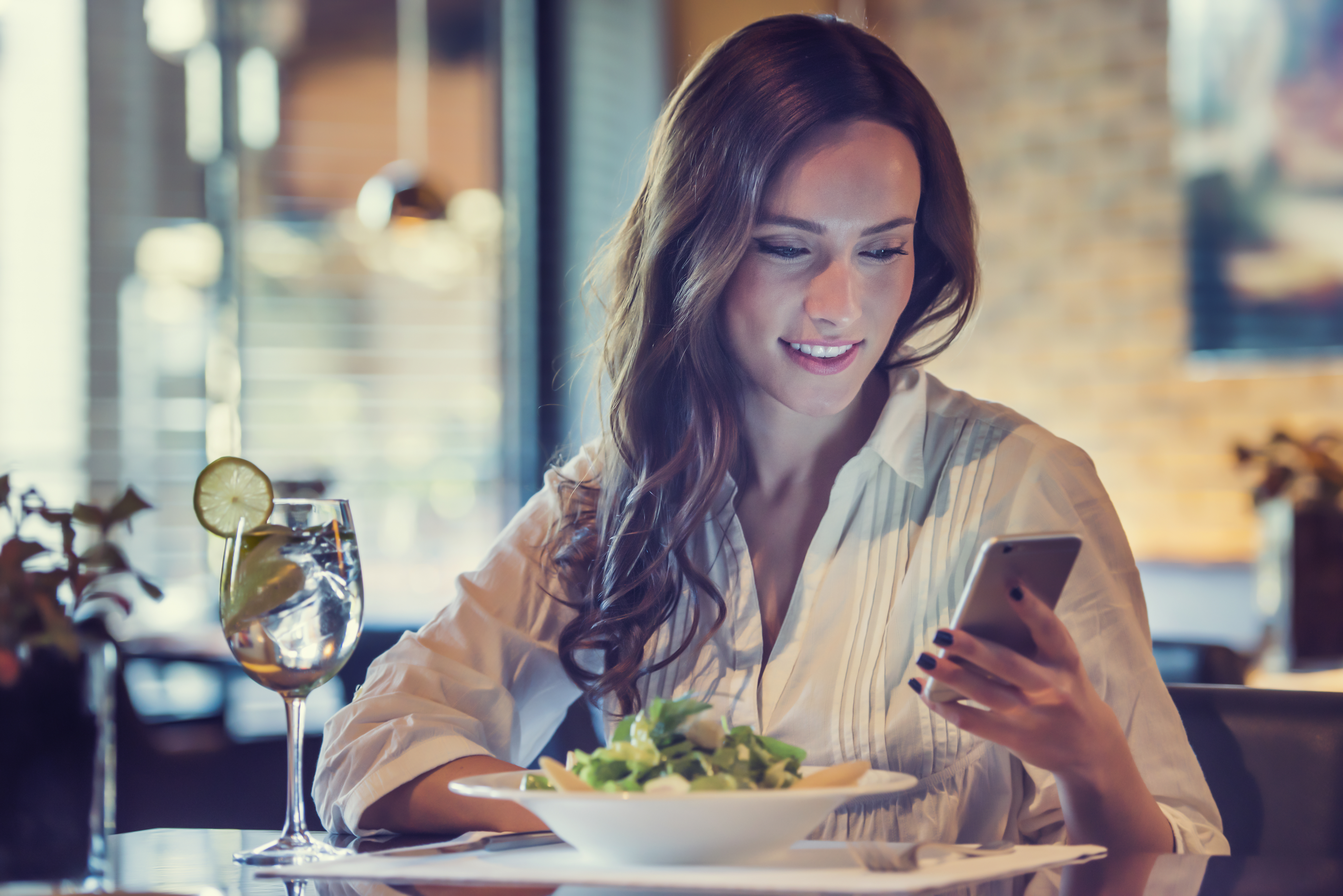 A young woman using her phone in a restaurant | Source: Shutterstock