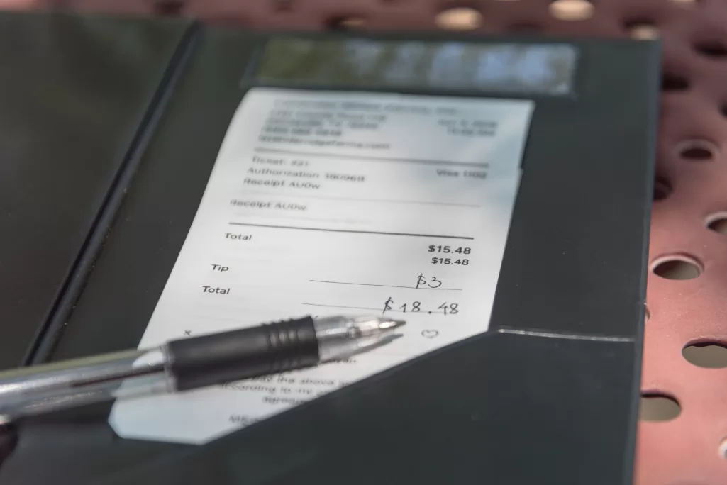 Open leather bill holder with restaurant check and pen | Source: Shutterstock