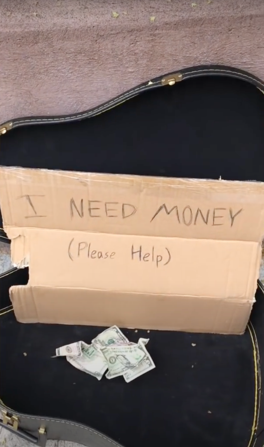 Jonathan's guitar case carrying a sign asking for money as he busks on the streets | Source: Youtube.com/bild