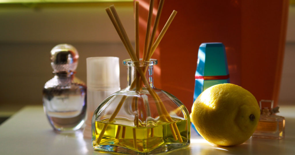 Fragrance diffusor glass with reed sticks between perfume flacons giving natural scent of lemon
