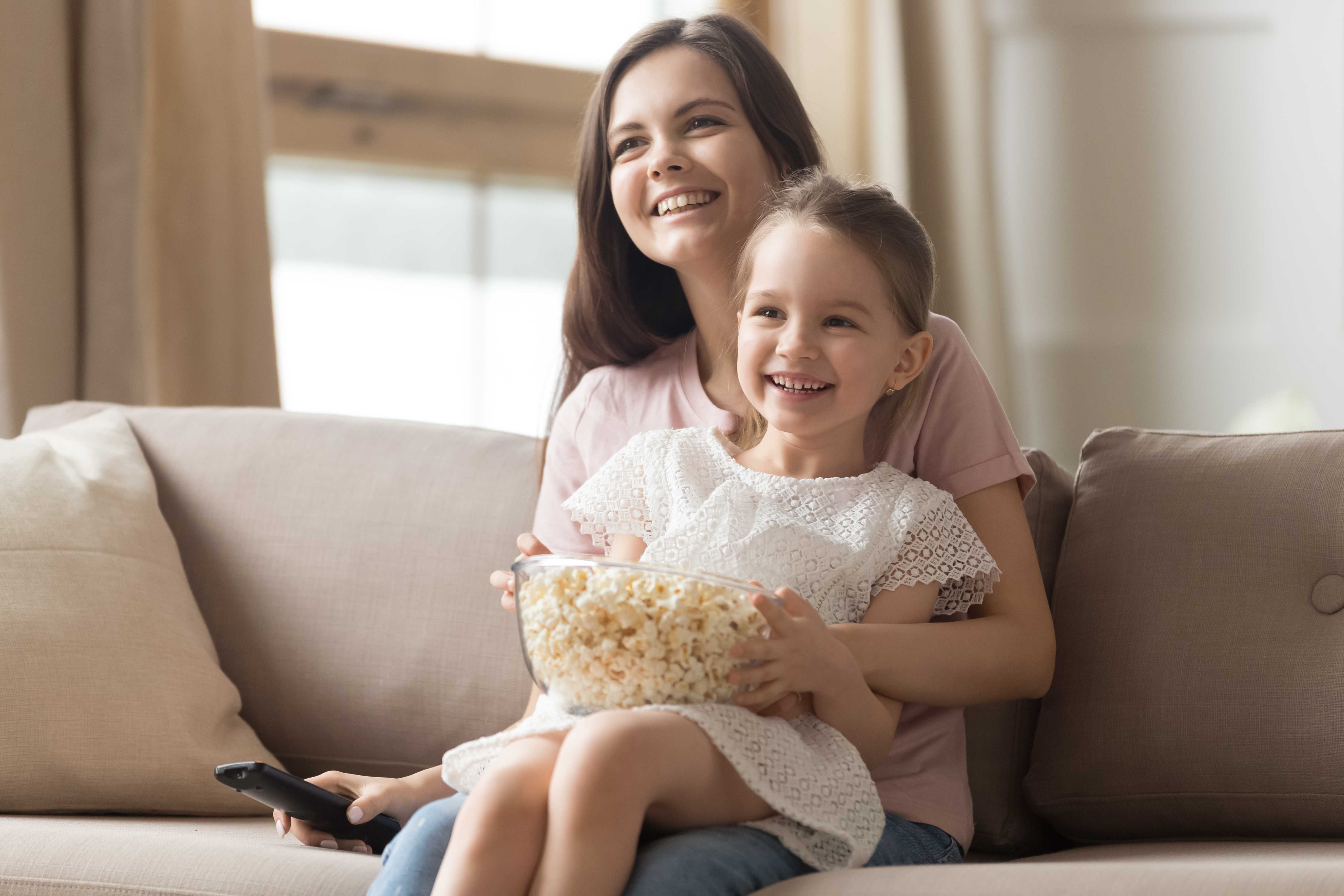 A happy young woman with a little girl smiling on her lap | Source: Shutterstock