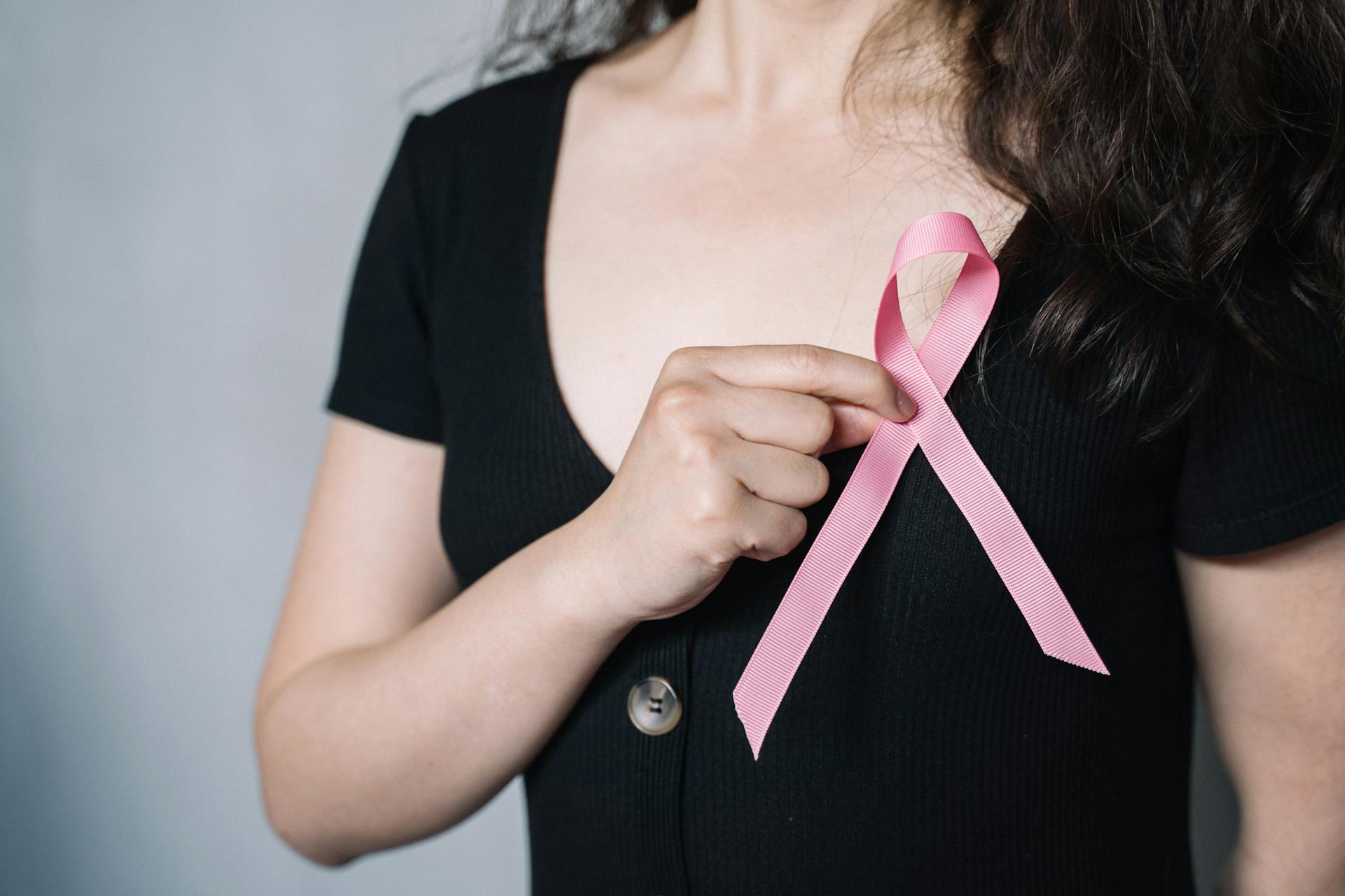 A young woman holding a pink ribbon | Source: Pexels