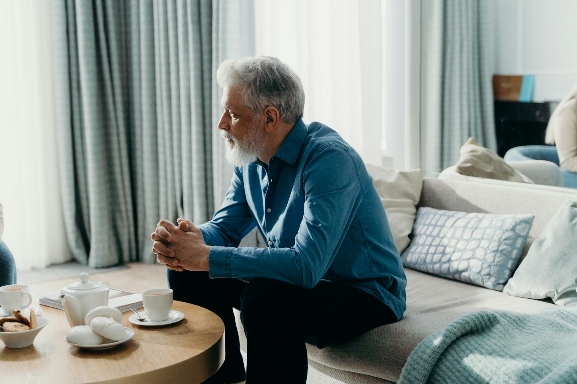 A senior man in a blue shirt sitting on the couch | Source: Pexels