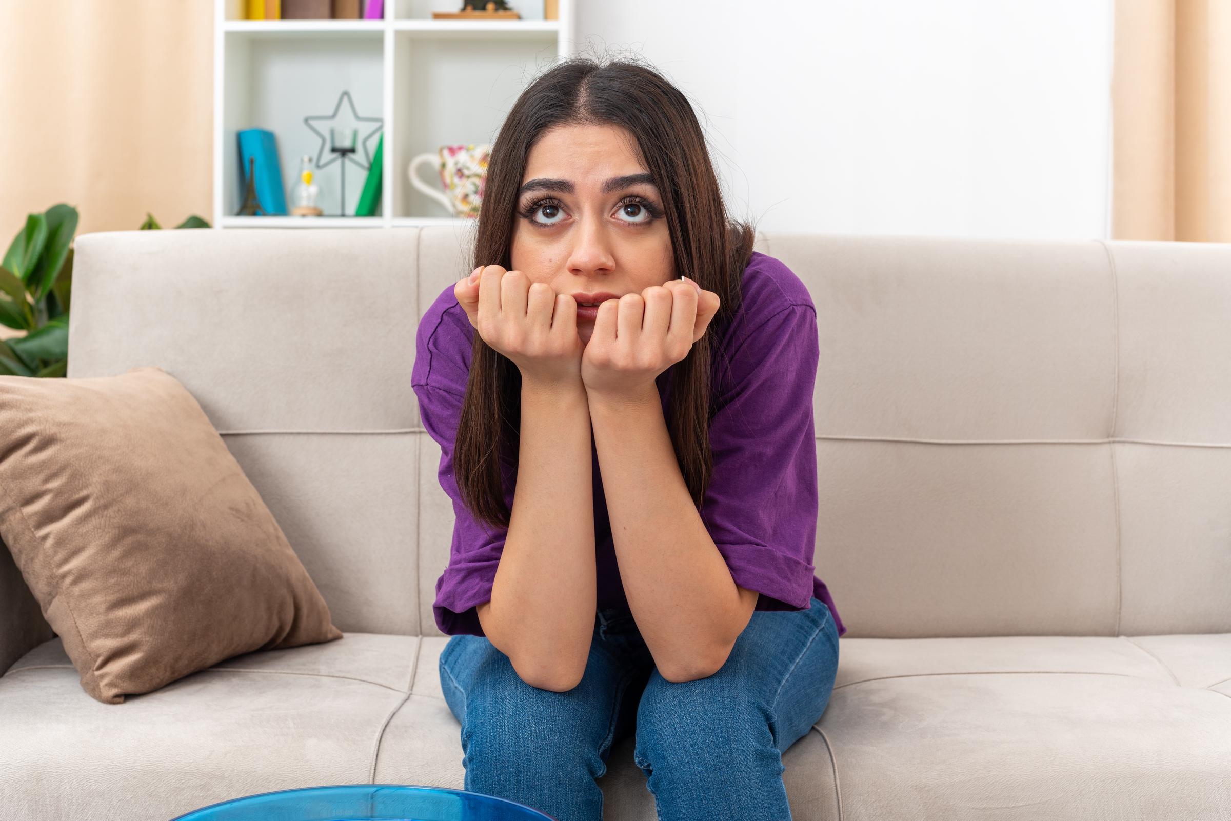 An upset young woman sitting on the couch | Source: Freepik