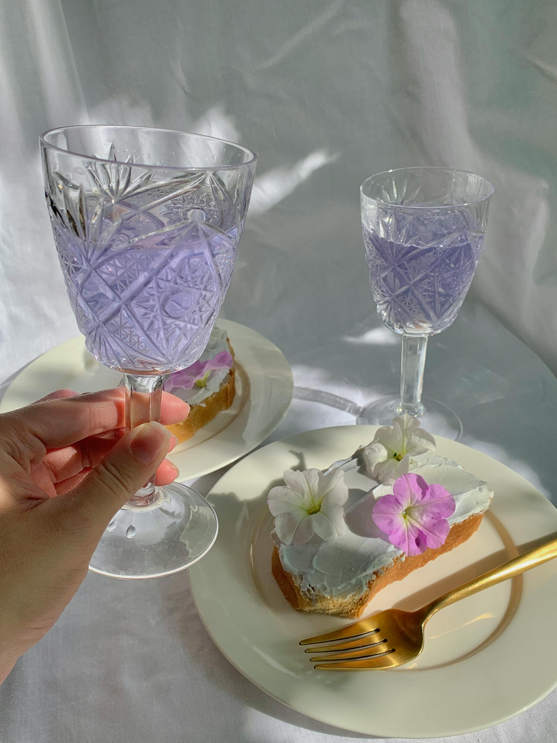 A person holding a goblet wine glass over a plate with flowers on bread | Source: Pexels