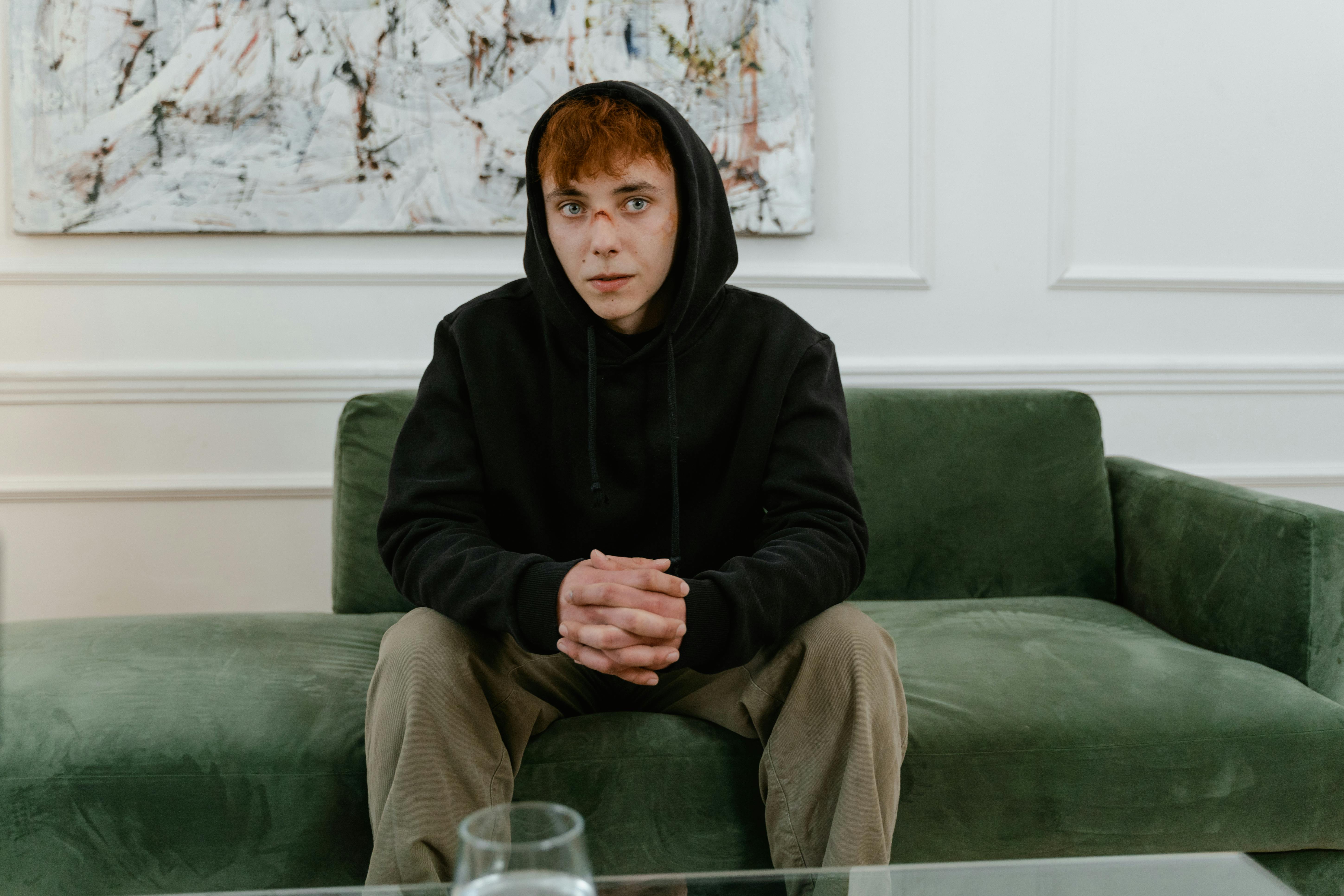 Sad young man seated on a couch | Source: Pexels