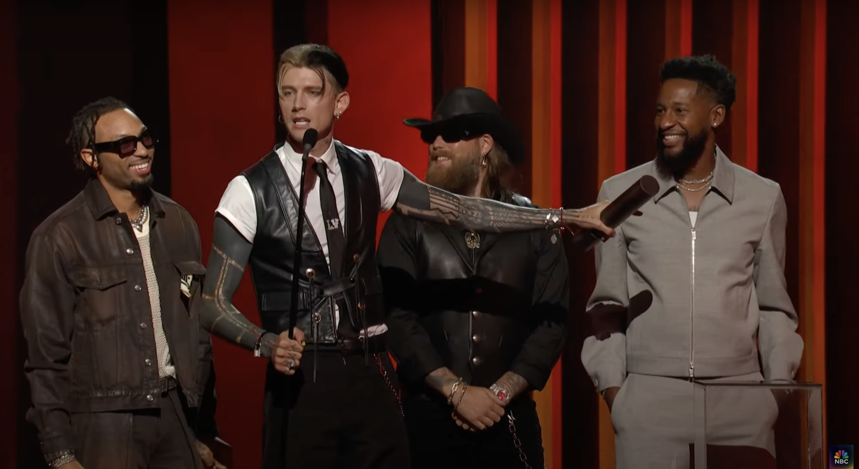 Machine Gun Kelly onstage with other attendees. | Source: YouTube/NBC