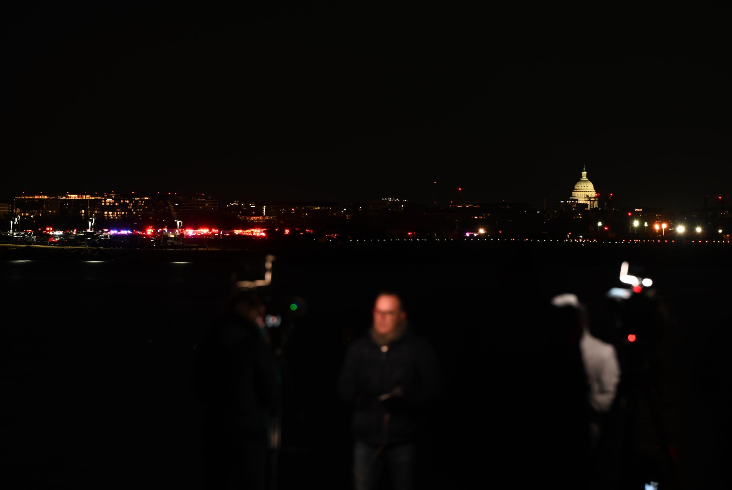 A view of the U.S. Capitol and reporters near where the crash happened in Washington, D.C., on January 30, 2025. | Source: Getty Images