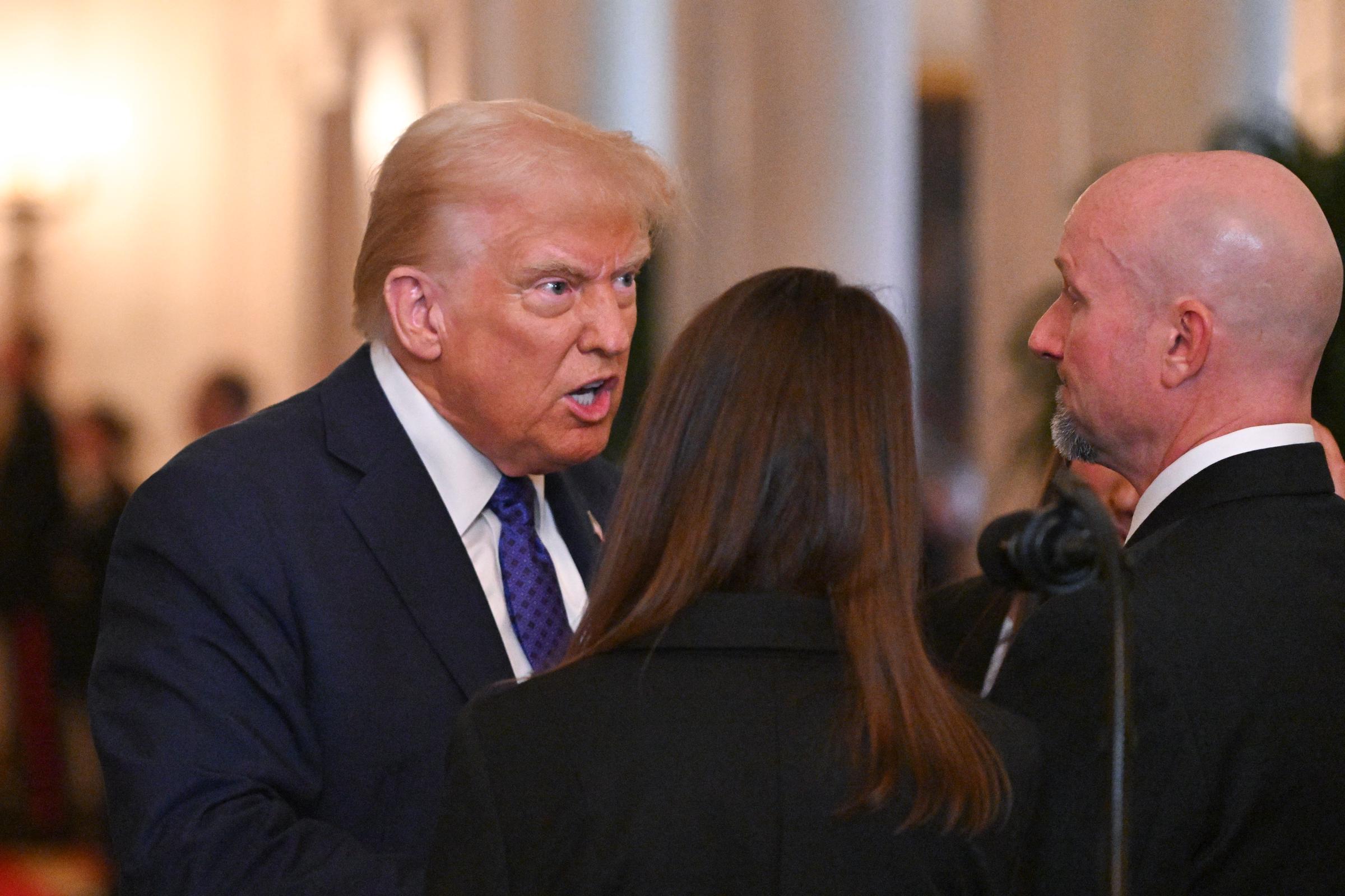 US President Donald Trump speaking with Allyson Phillips, mother of Laken Riley, and John Phillips, stepfather of Laken Riley, before signing the Laken Riley Act in the East Room of the White House in Washington, D.C., January 29, 2025. | Source: Getty Images