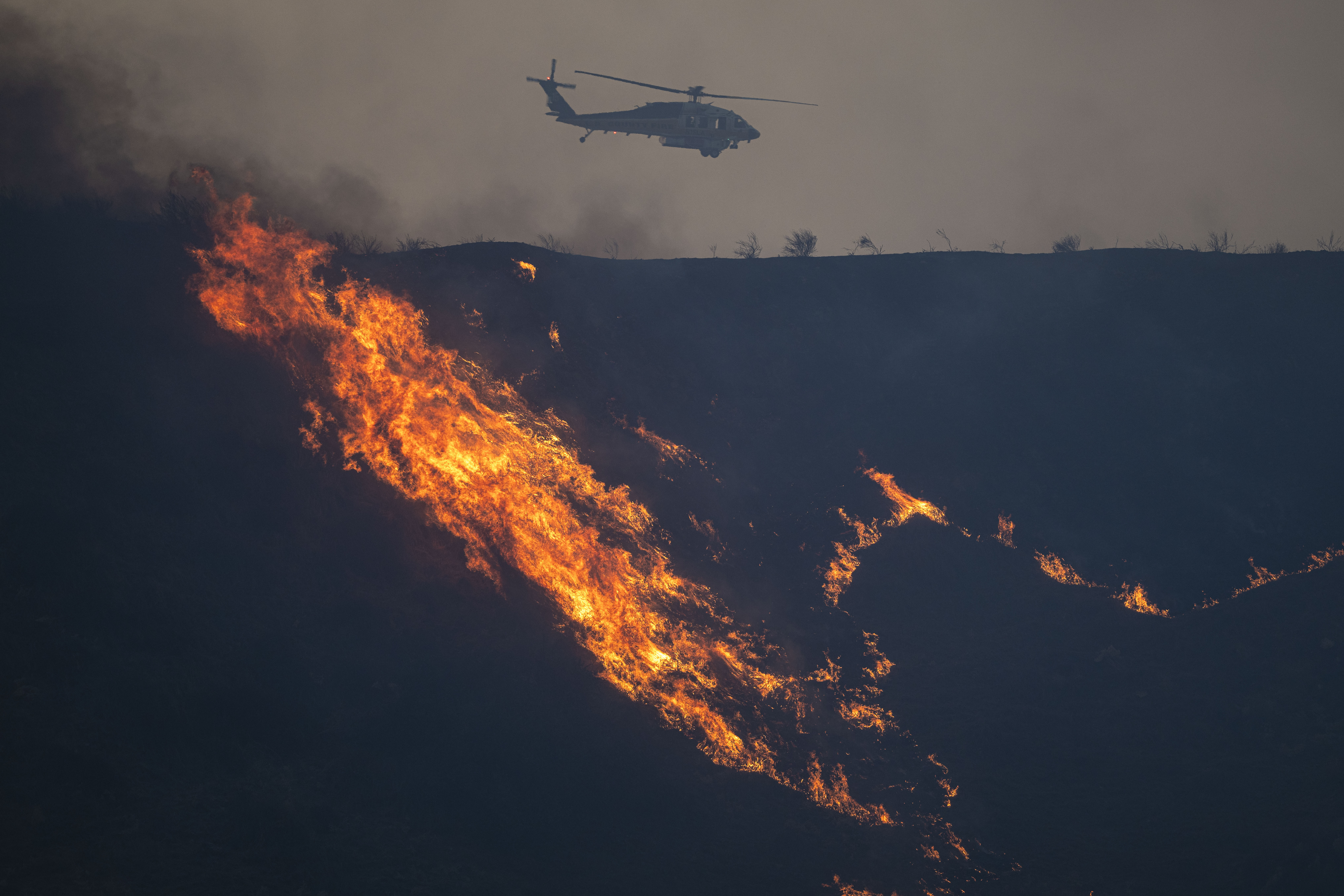 An LA County helicopter drops water drop over the Hughes Fire in California on January 22, 2025 | Source: Getty Images