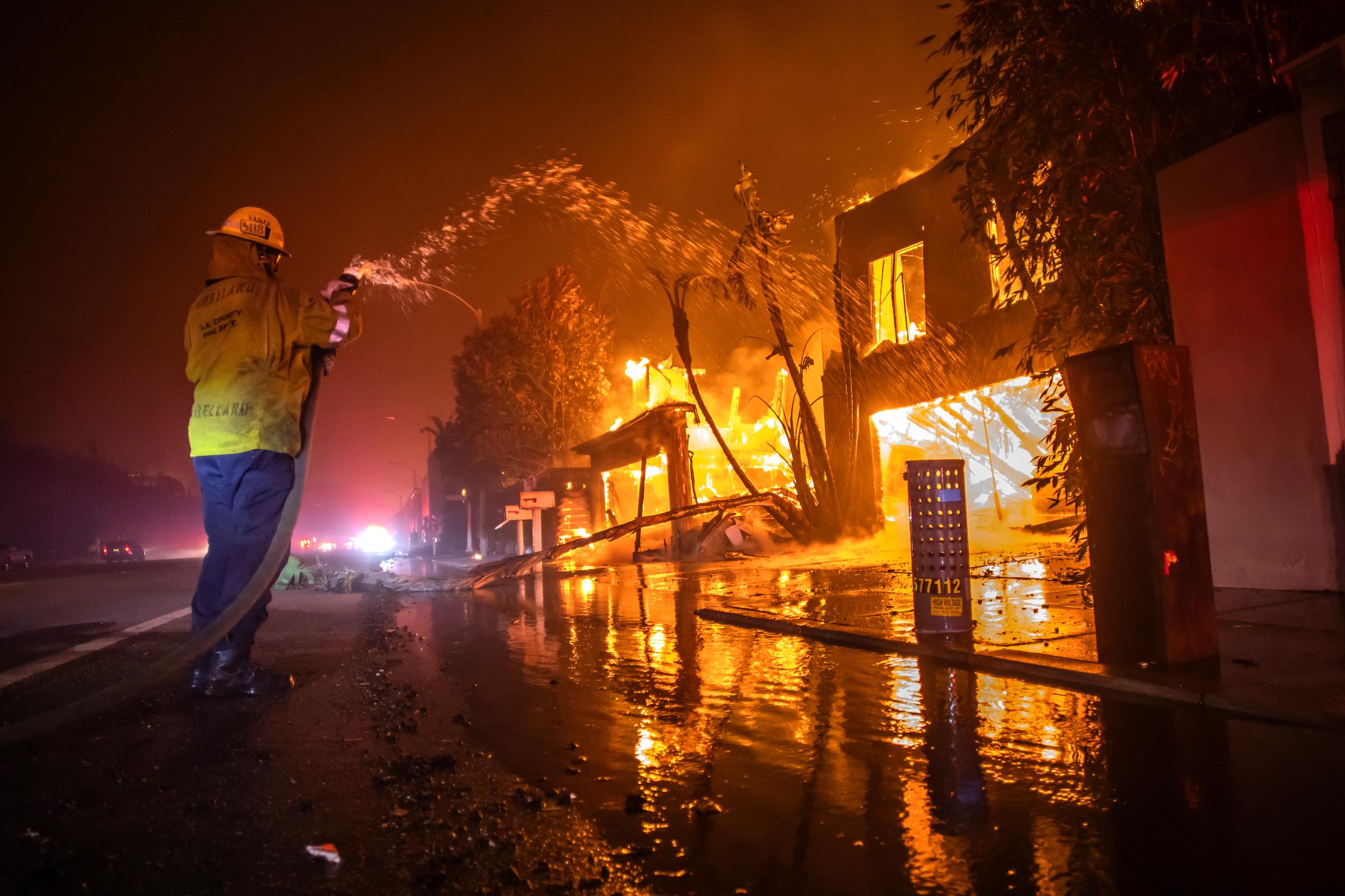 A firefighter battles the Palisades Fire while it burns homes at Pacific Coast Highway amid a powerful windstorm in Los Angeles, California, on January 8, 2025 | Source: Getty Images