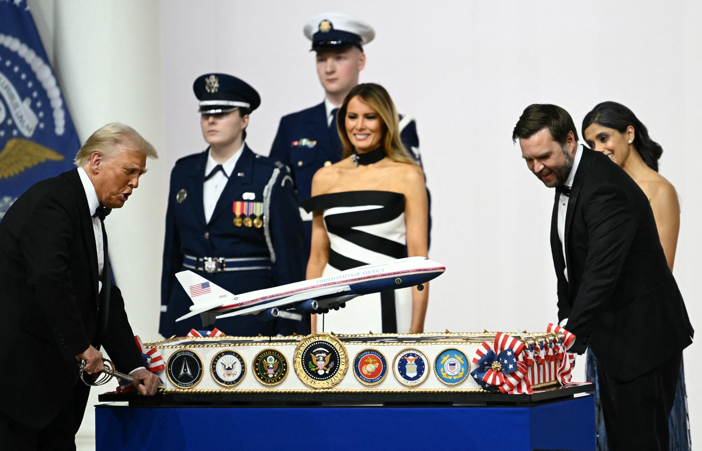 First Lady Melania Trump next to Usha Vance watch US President Donald Trump and Vice President J.D. Vance cut into a cake representation of the new Air Force One design with a saber, during the Commander-In-Chief inaugural ball, on January 20, 2025 | Source: Getty Images