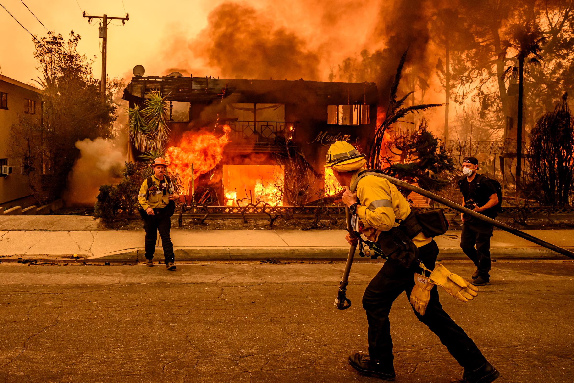 Firefighters work the scene as an apartment building burns during the Eaton fire in the Altadena area of Los Angeles county, California, on January 8, 2025 | Source: Getty Images