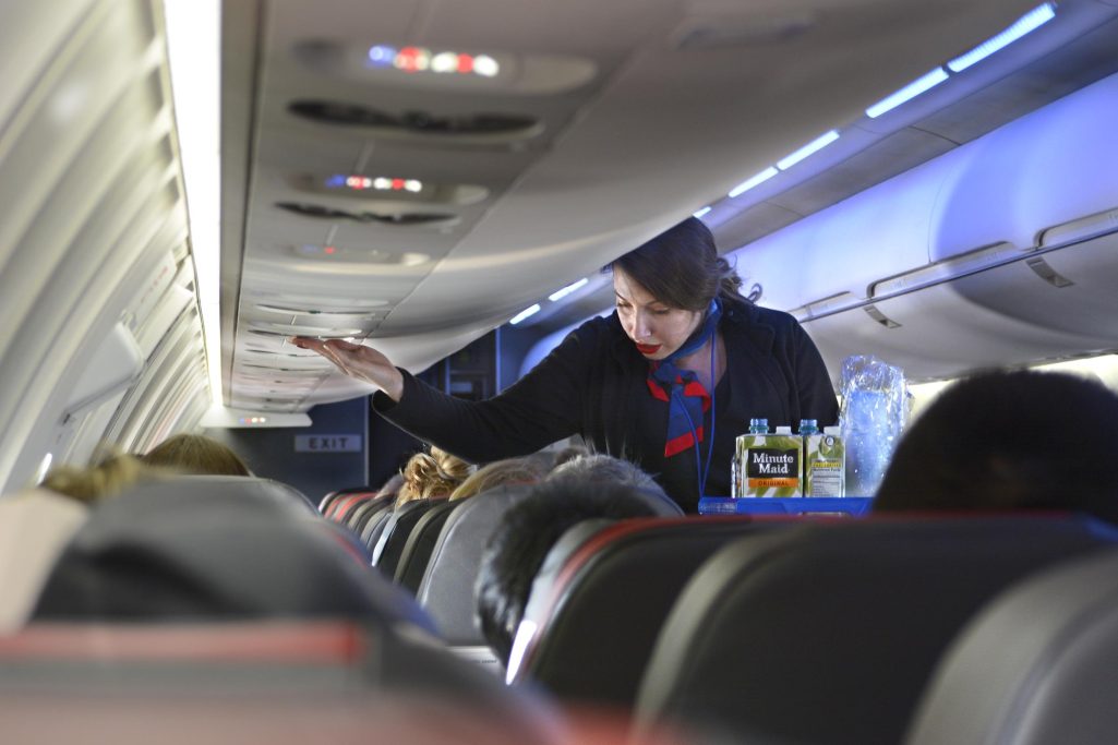 An American Airlines flight attendant serves drinks to passengers after departing Dallas/Fort Worth International Airport | Source: Getty Images