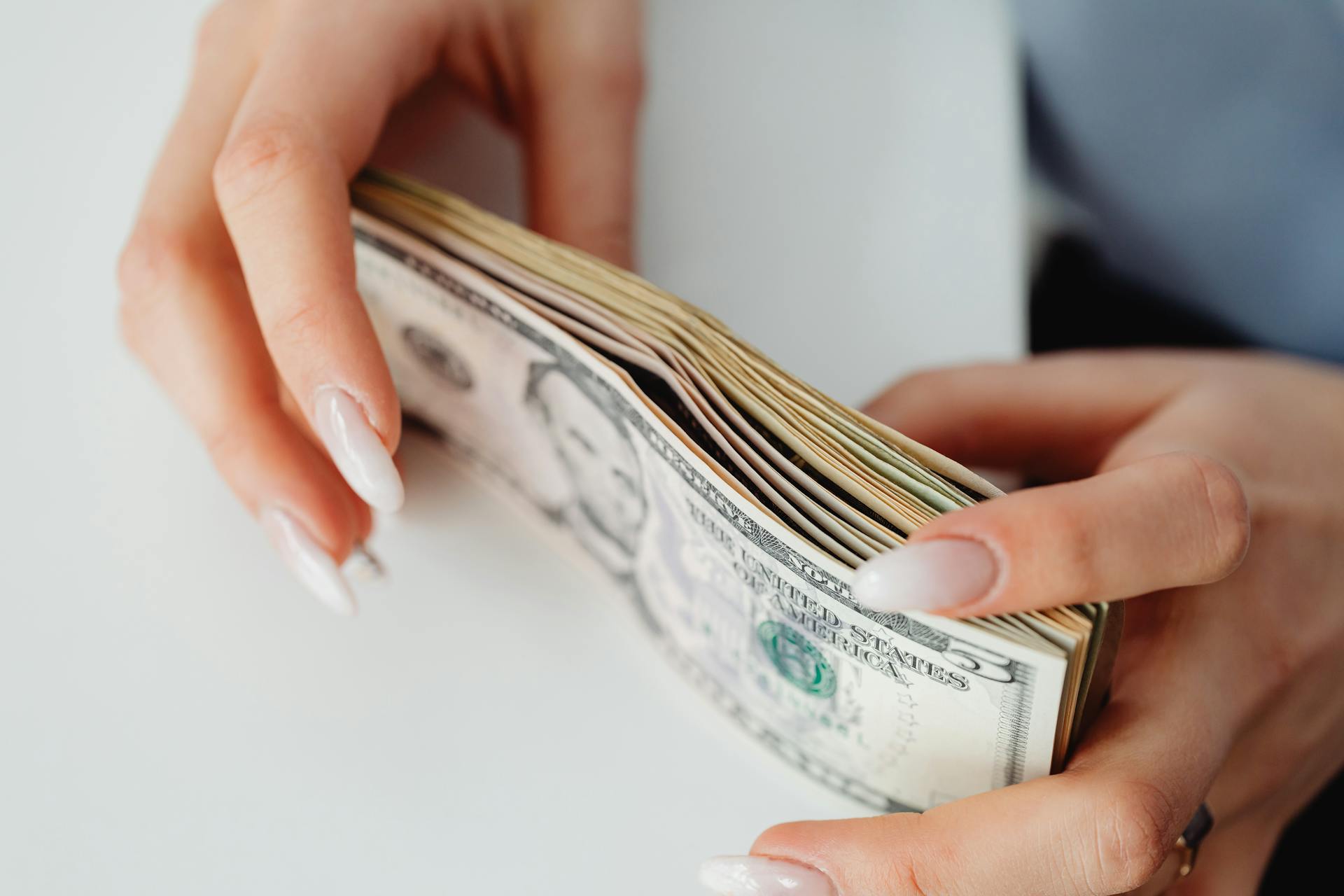 Close-up shot of a woman holding a bundle of cash | Source: Pexels