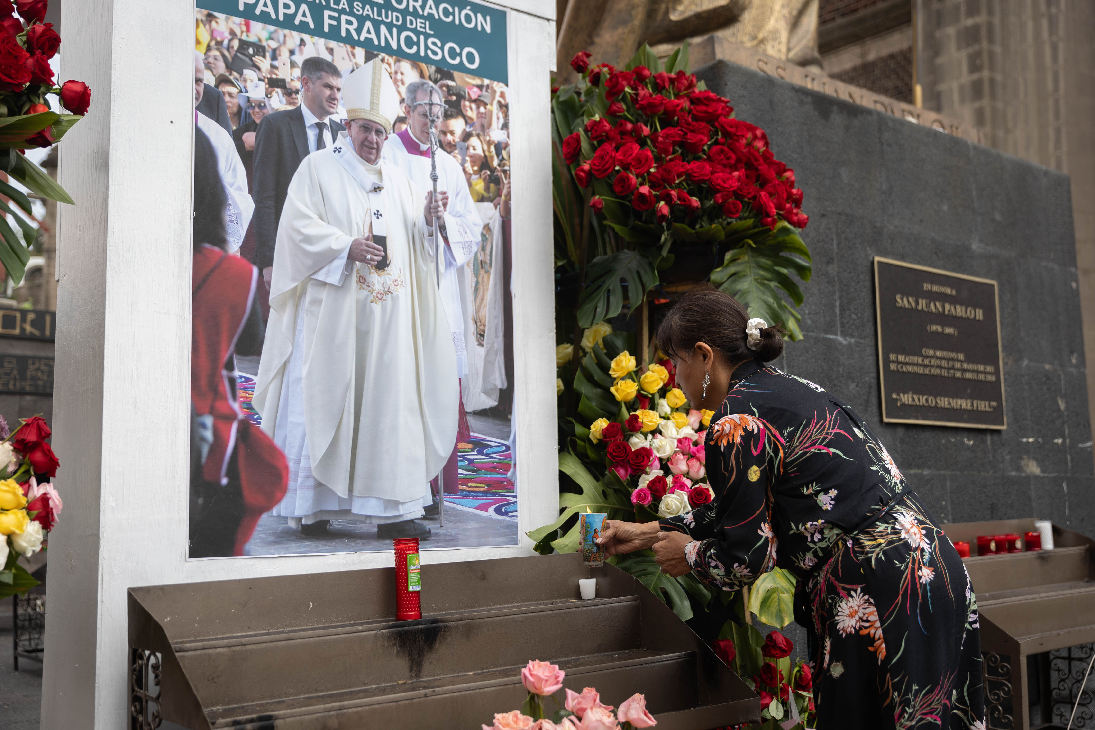 A woman placing a candle in front of an image of Pope Francis outside the Basilica de Guadalupe, in Mexico City, Mexico, on February 23, 2025. | Source: Getty Images