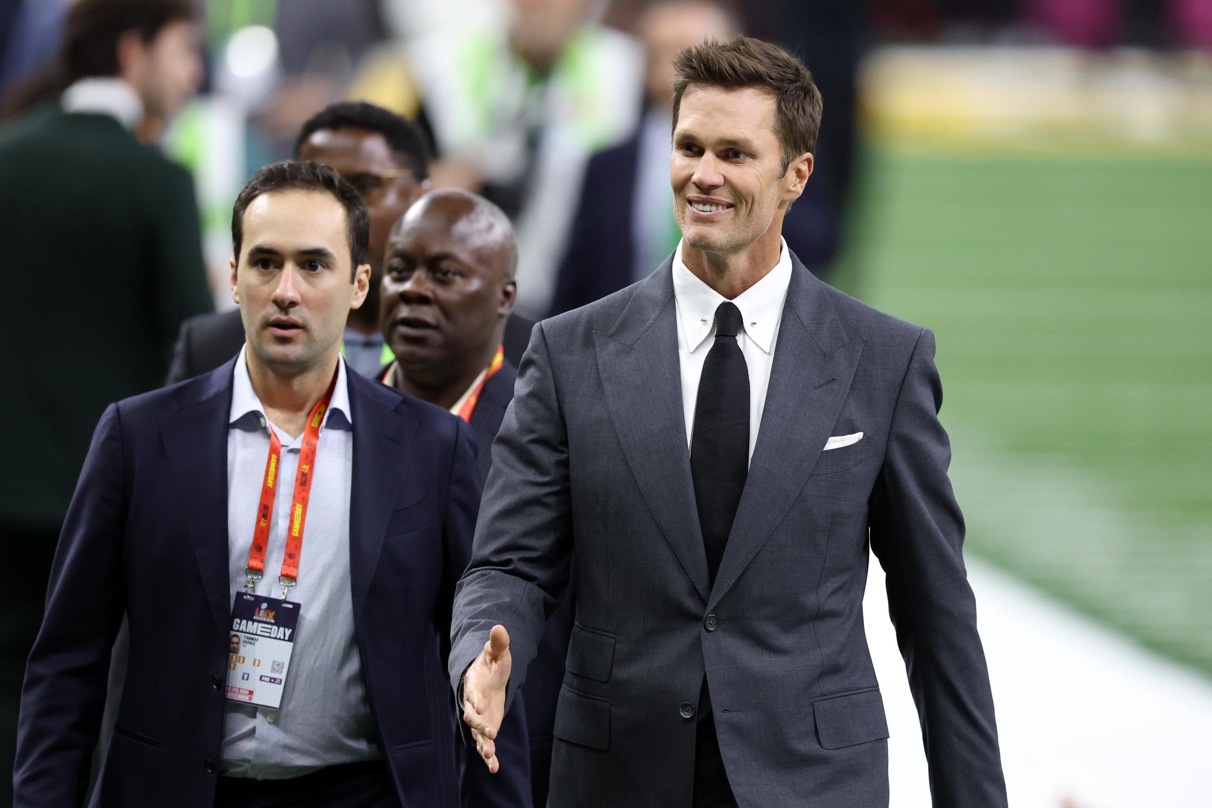 Tom Brady walking across the field with people at the Super Bowl. | Source: Getty Images