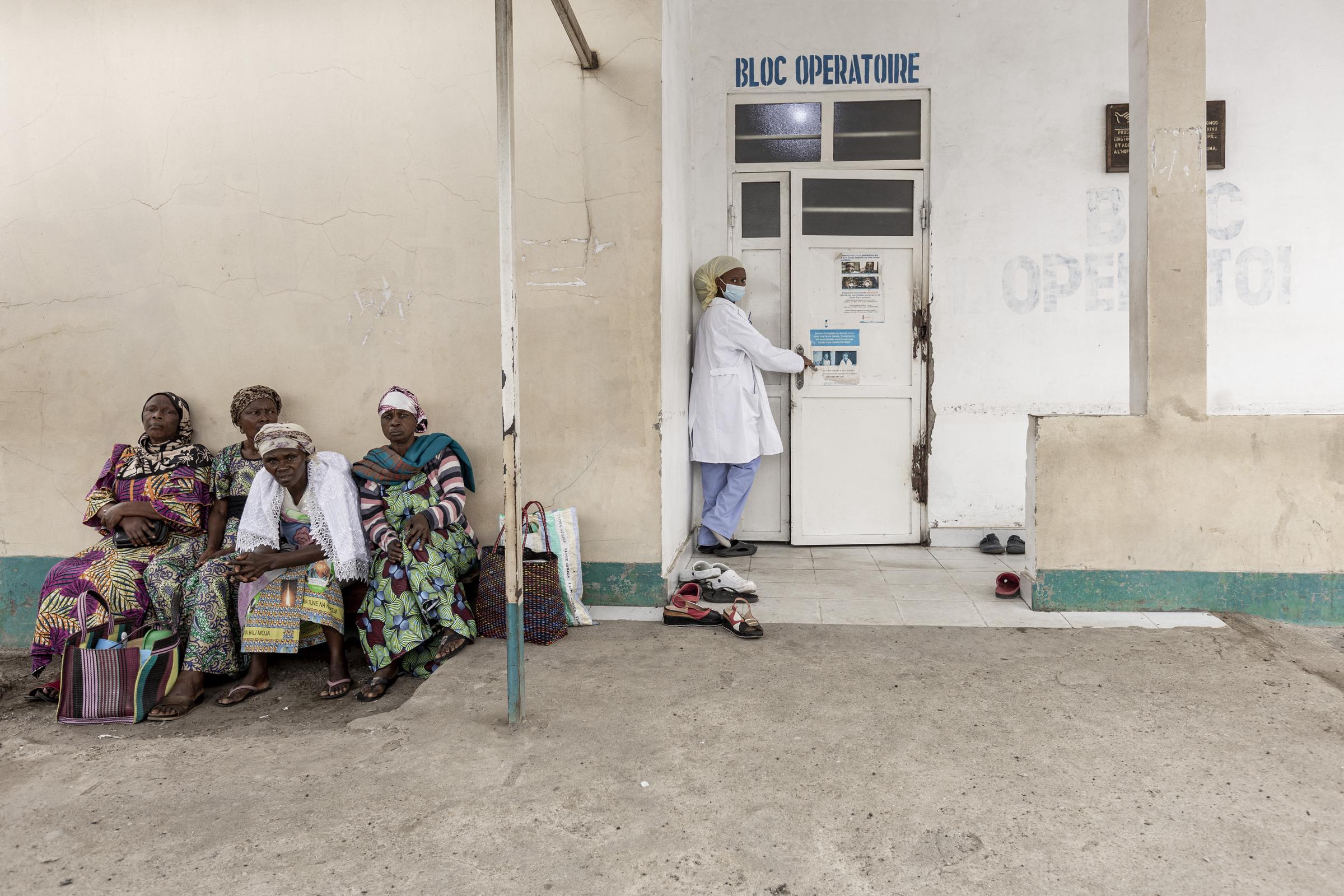 A nurse enters the operating room at a hospital in the Democratic Republic of Congo as women wait outside | Source: Getty Images