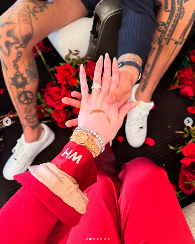 Winnie Harlow holds hands with Kyle Kuzma, showcasing her dazzling engagement ring against a backdrop of scattered red roses | Source: Instagram/winnieharlow