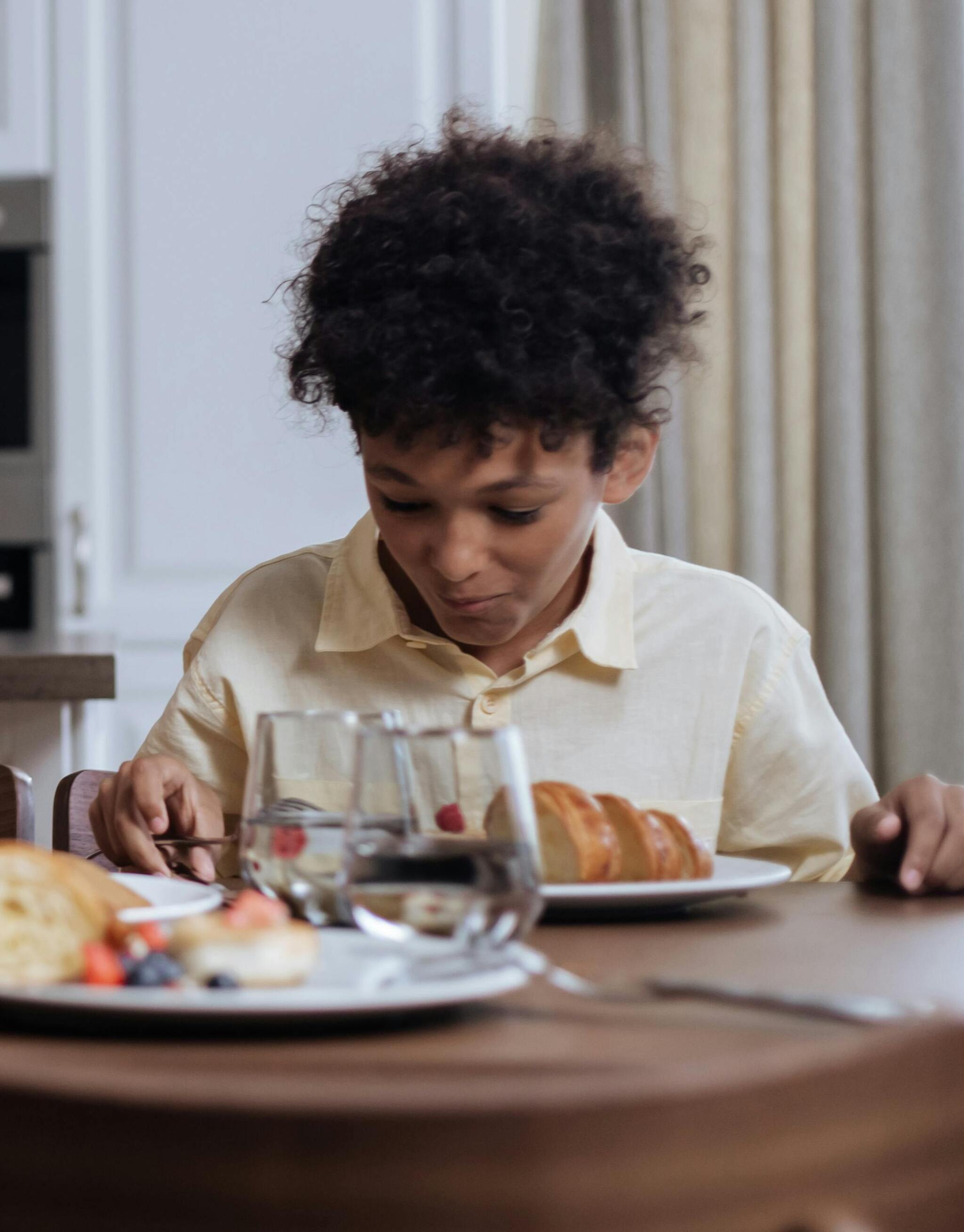 A kid eating at a kitchen table | Source: Pexels