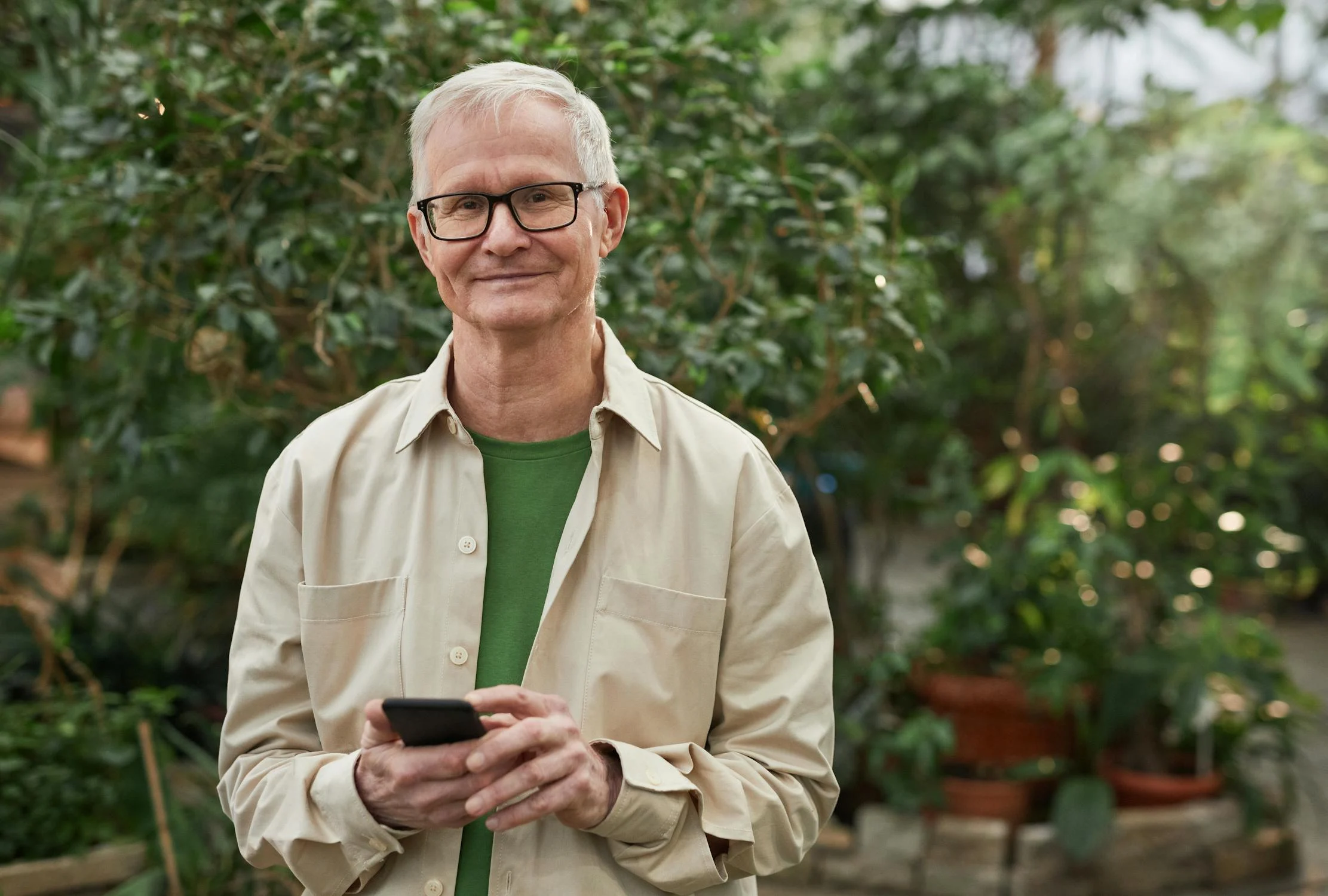 A smiling man holding his phone ⏐ Source: Pexels