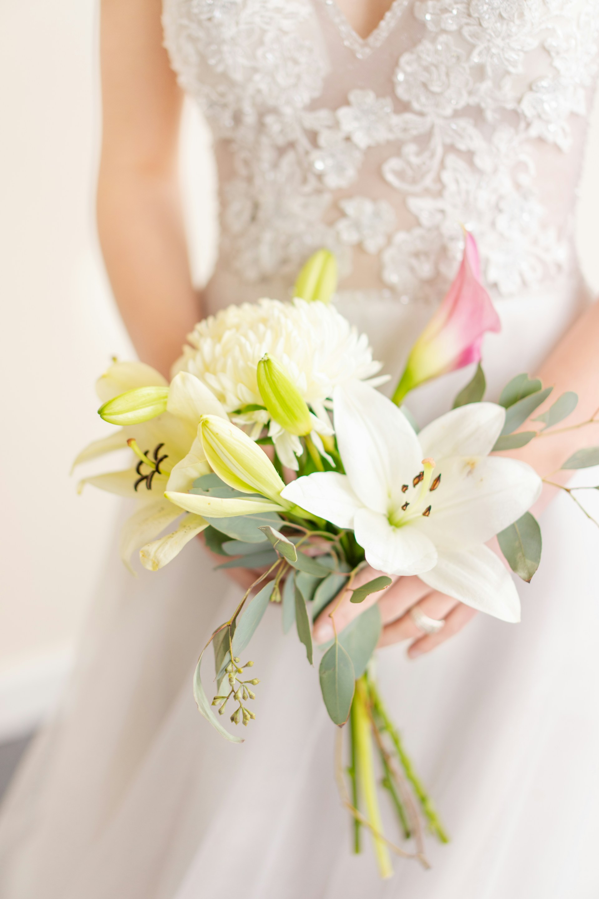 Close-up cropped shot of a bride holding a bouquet of lilies | Source: Unsplash